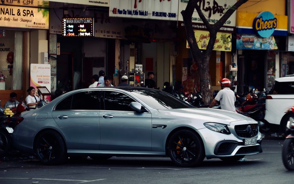 A high-end silver car parked on a bustling urban street, capturing city life.